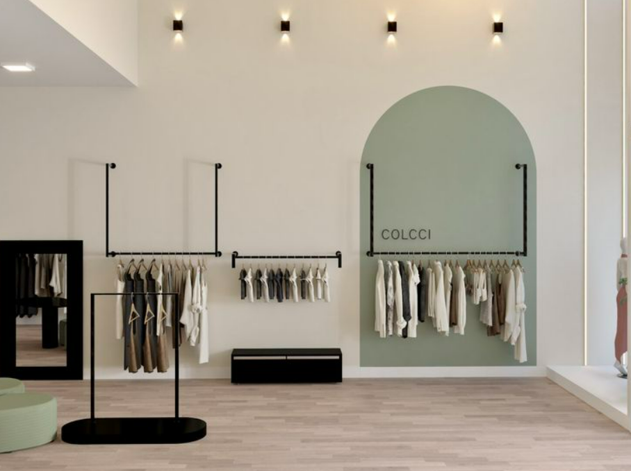 Loja de roupas com araras pretas de parede e de chão em ambiente claro